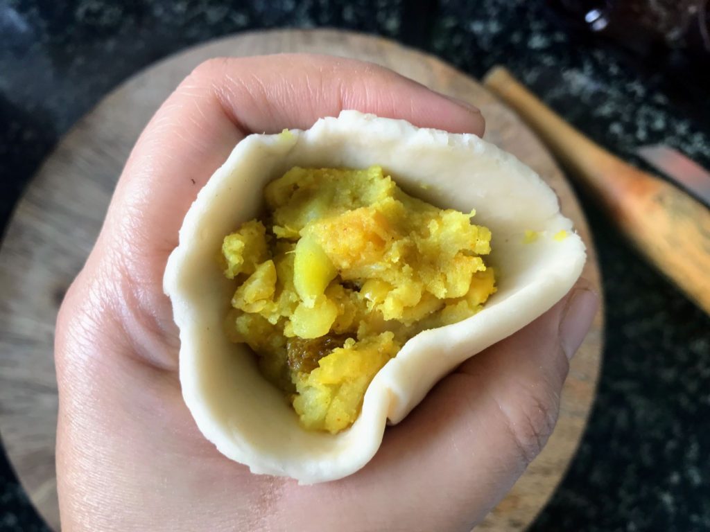 Filling dough to make samosa